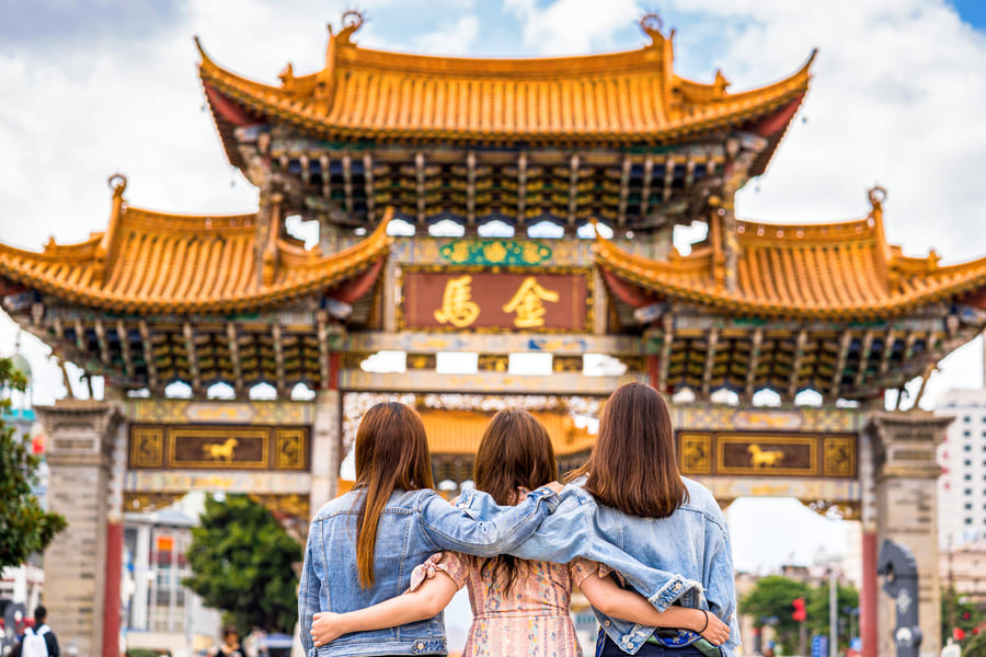 3 Mujeres abrazadas viendo una edificación china antigua
